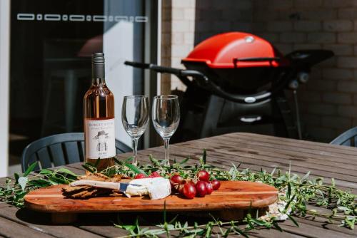 a bottle of wine and two glasses on a wooden table at Gladstone at The Willows - Family Time, Mudgee Style in Mudgee
