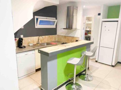 une cuisine avec un comptoir et des tabourets verts et blancs dans l'établissement Petit duplex Aéroport de Marseille et Plages, à Marignane