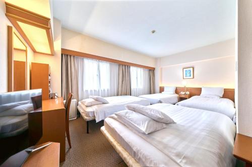 a hotel room with three beds and a window at Daiichi Inn Ikebukuro in Tokyo