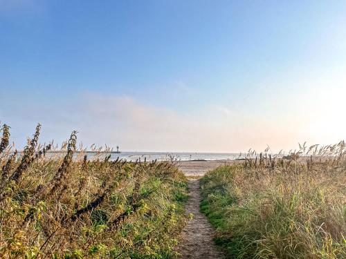 a path to the beach with the ocean in the background at Strandblick - Dorf 1 Ferienhaus 09 in Priwall
