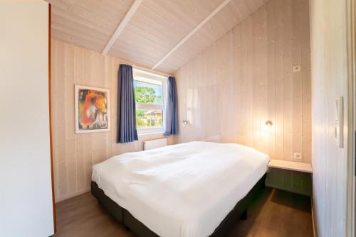 a bedroom with a large white bed with a window at Strandblick - Dorf 1 Ferienhaus 09 in Priwall
