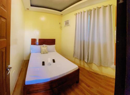 a bedroom with a large bed with white sheets and a window at Rb's Three Storey House in Zamboanga