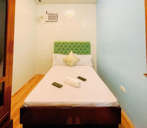 a small bedroom with a bed with a green headboard at Rb's Three Storey House in Zamboanga