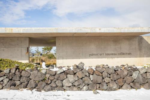 a building with a rock wall in front of it at Phoenix Island in Seogwipo