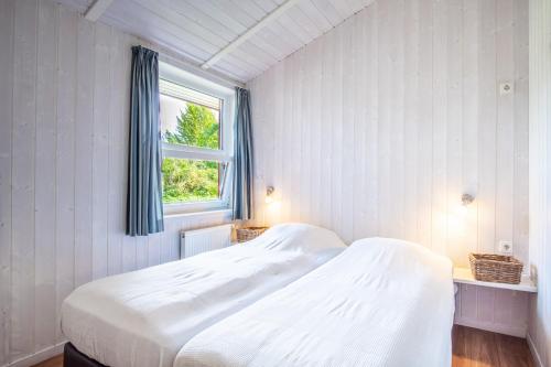 a white bed in a room with a window at Strandblick - Dorf 1 Ferienhaus 07 in Priwall