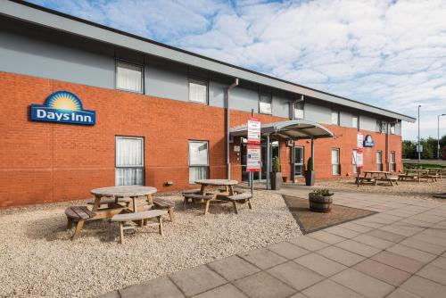 a building with picnic tables and benches in front of it at Days Inn by Wyndham Telford Ironbridge in Telford
