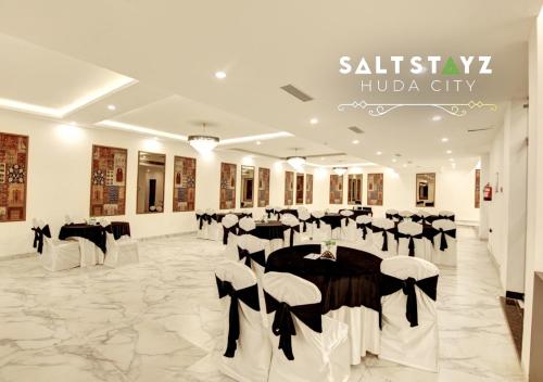 a banquet hall with black and white tables and chairs at Saltstayz Select - Near Millennium City Centre in Gurgaon