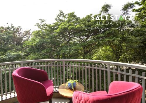 two chairs and a table on a deck with a fence at Saltstayz Select - Near Millennium City Centre in Gurgaon