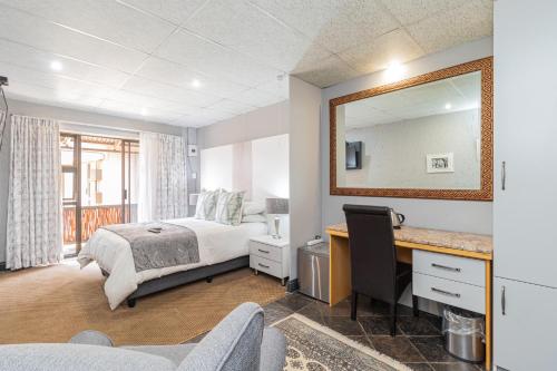 a bedroom with a bed and a desk and a mirror at Gold Crest Guesthouse in Roodepoort