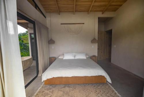 a bedroom with a bed and a large window at The Oasis, Jungle Sanctuary in Barú