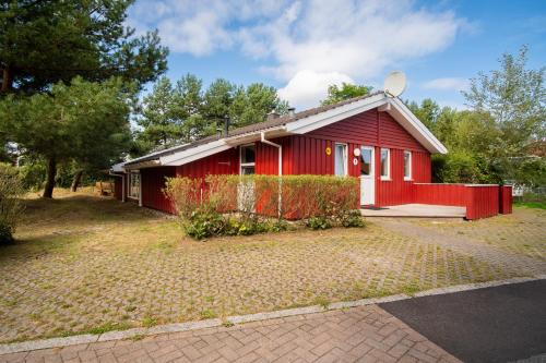 a red house with a red fence in front of it at Strandblick - Dorf 1 Ferienhaus 01 in Priwall