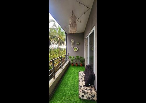 a room with green grass and a balcony with a window at Boho 44 in Goa