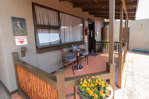 a porch with two chairs and a table and flowers at Gold Crest Guesthouse in Roodepoort