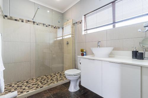 a bathroom with a toilet and a shower and a sink at Gold Crest Guesthouse in Roodepoort