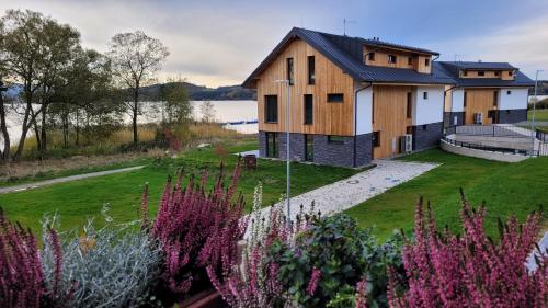 a house with a garden in front of a lake at Apartmán AMALI Deluxe in Černá v Pošumaví