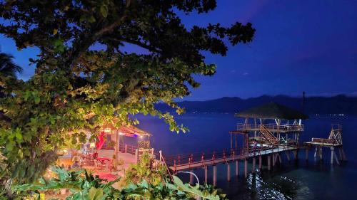 a dock with a restaurant on the water at night at Chue&larry's Beachside Homestay in Libagon
