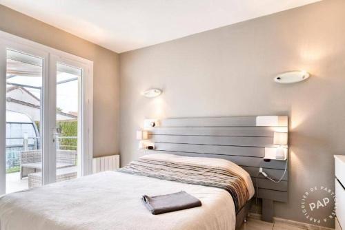 une chambre avec un lit et une grande fenêtre dans l'établissement maison avec piscine chaufée couverte d'avril à fin octobre, à Ranville