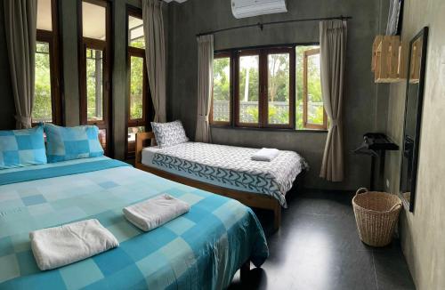 a bedroom with two beds and a chair and windows at Ban Chomchan Pool Villa Khaoyai in Ban Tha Chang