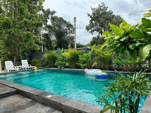a swimming pool in a yard with two chairs in it at Ban Chomchan Pool Villa Khaoyai in Ban Tha Chang