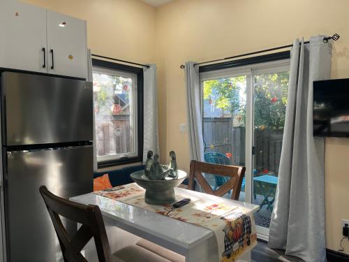 a kitchen with a table and a stainless steel refrigerator at The Grassy Oasis in Brampton