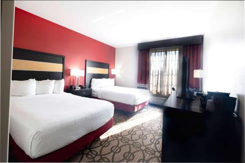 a hotel room with two beds and a flat screen tv at La Quinta by Wyndham Starkville at MSU in Starkville