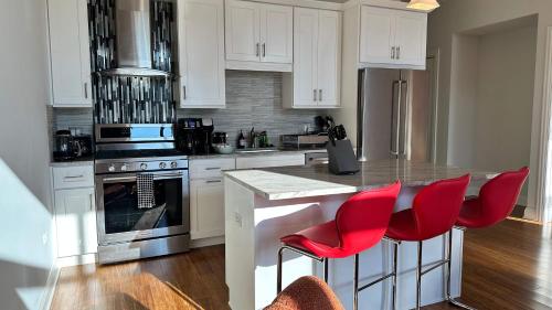 a kitchen with white cabinets and red chairs in it at Chic 2 BR 1 Parking Sleeps 6 in Chicago