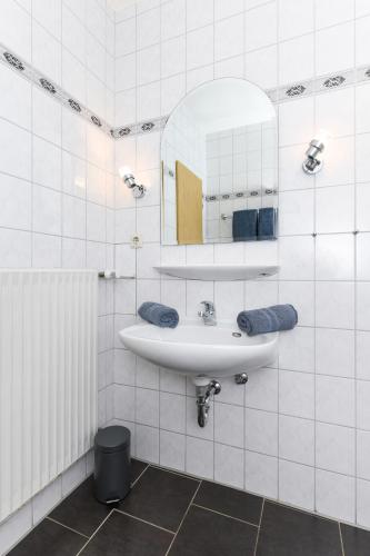 a white bathroom with a sink and a mirror at Haus Hafenromantik in Neuharlingersiel