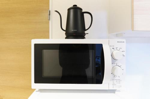 a black tea kettle sitting on top of a microwave at Maison Asch Ikebukuro by Tranova in Tokyo