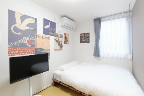 a bedroom with a bed and a flat screen tv at Maison Asch Ikebukuro by Tranova in Tokyo