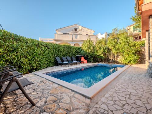 マリンスカにあるVilla Badiの建物の隣に椅子2脚付きのスイミングプール