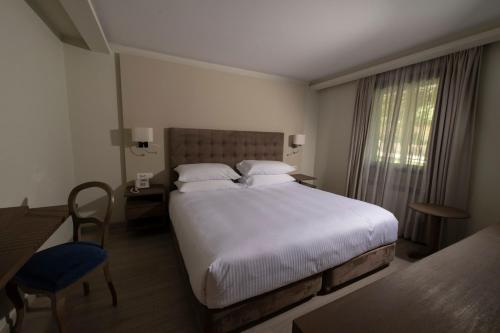 a bedroom with a large bed and a table and chair at InterContinental Mzaar Lebanon Mountain Resort & Spa by IHG in Kfardebian