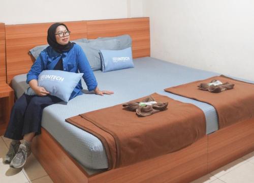 una mujer sentada en una cama con dos camas en Intech Hostel, en Bandung