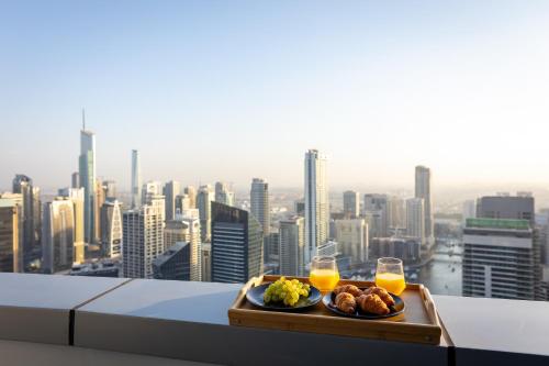 a tray of food and two glasses of orange juice at Dubai Marina 3BR Penthouse with Stunning JBR, Marina & Dubai Eye Views in Dubai