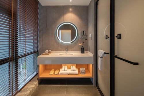a bathroom with a sink and a mirror at 重庆文里苗品茶艺术酒店Chongqing Jiangbei Airport Creative Park Store in Renhe