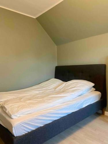 a bed with white sheets and a black headboard in a room at Luxurious villa - exceptional location in city center with free P in Odense