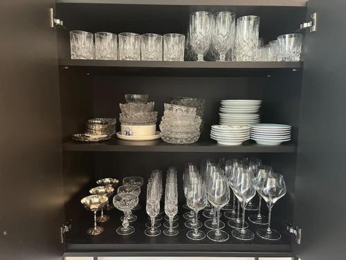 a shelf filled with wine glasses and plates at Luxurious villa - exceptional location in city center with free P in Odense