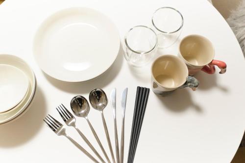 a table with plates and cups and forks and spoons at Maison Asch Ikebukuro by Tranova in Tokyo