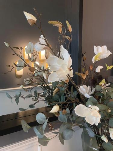 a vase with white flowers in front of a mirror at Luxurious villa - exceptional location in city center with free P in Odense