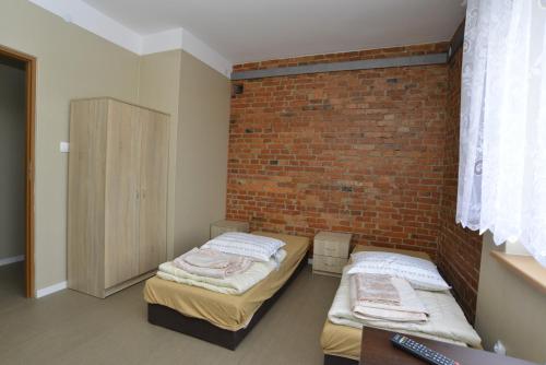 two beds in a room with a brick wall at Mieszkanie - kawalerka in Skarżysko-Kamienna