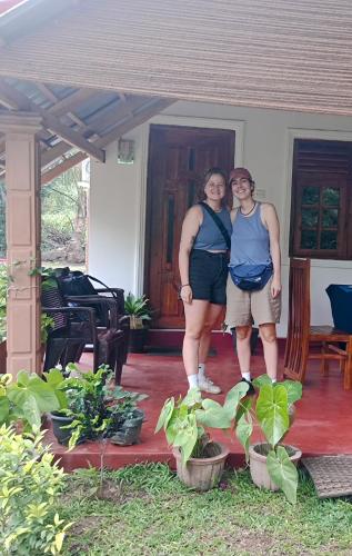 two people standing on the porch of a house at Jungle Eco Lodge & Safari in Sigiriya