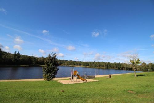 a park with a playground next to a lake at Gîte Les Champs N°2 in Saint-Mathieu