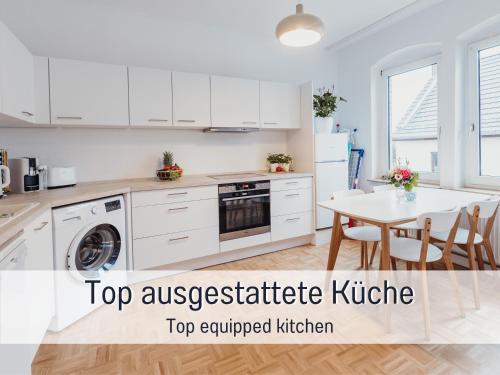 a kitchen with white cabinets and a white table at Wohlfühloase in Kirchditmold - Netflix und gute Anbindung an Innenstadt und Weltkulturerbe Bergpark Wilhelmshöhe in Kassel