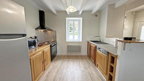a large kitchen with wooden cabinets and a refrigerator at Gîte Les Champs N°3 in Saint-Mathieu