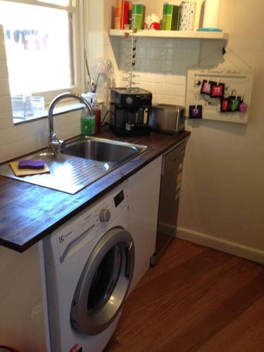 a kitchen with a sink and a washing machine at Picture Perfect Toorak, entire apartment in Melbourne