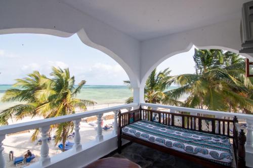 a balcony with a bench looking out at the beach at Jacaranda Beach Resort in Watamu