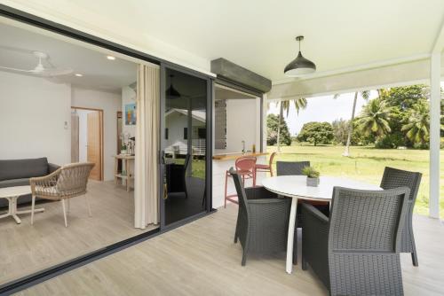 a dining room and living room with a table and chairs at Raina Lodge - Fare Hereiti - Piscine privée in Paeau