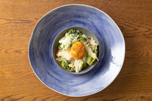 a blue bowl of food on a wooden table at The Cellars-Hohenort in Cape Town