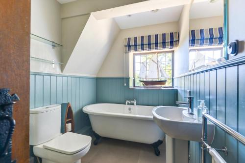 a bathroom with a tub and a sink and a boat in the window at Oldfield house, walking distance of pub & sea in West Itchenor