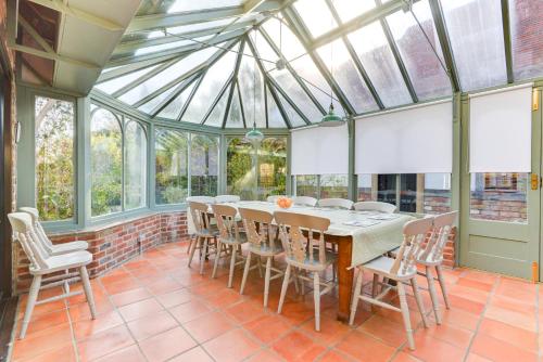 a glass conservatory with a table and chairs at Oldfield house, walking distance of pub & sea in West Itchenor