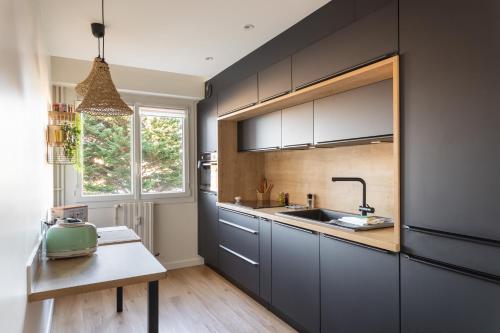 - une cuisine avec des placards gris, un évier et une table dans l'établissement Le Ty Sillon - Appt proche de la plage, à Saint-Malo